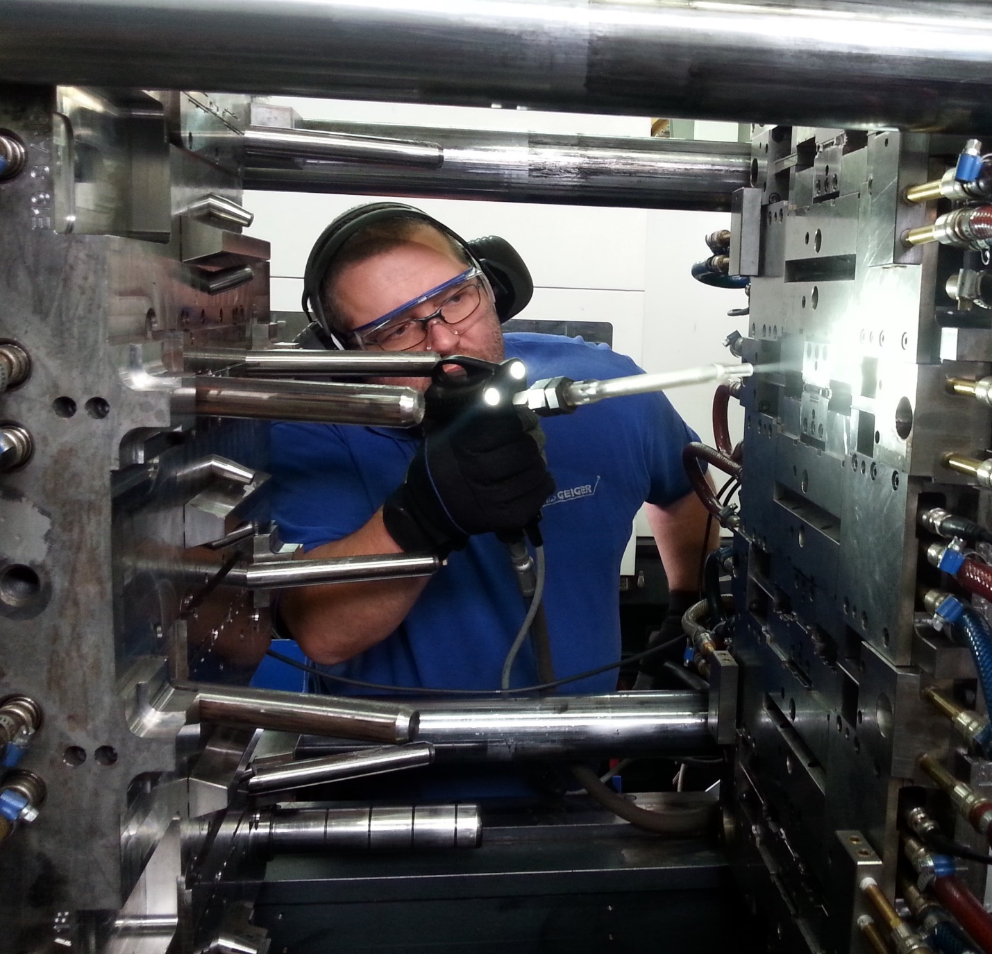 Técnico limpando um molde de injeção plástica com um bico de jateamento de gelo seco.