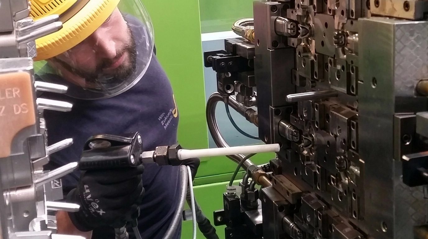 Operador a limpar com gelo seco um molde de injeção de plástico na máquina com uma pistola Cold Jet