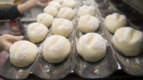 Tabuleiro com bolas de massa de pão enfarinhadas numa linha de produção de padaria industrial